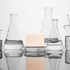 Basic Maintenance Formula 10 The Cleansing Clay shown standing between lab glassware